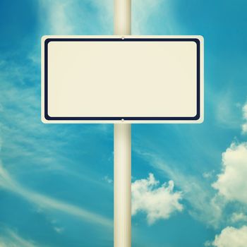 Blank road signs, empty street post, blue sky background in vintage style.