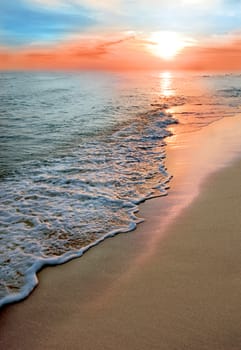 Vertical image of the sea and the beach. Sunrise small wave.