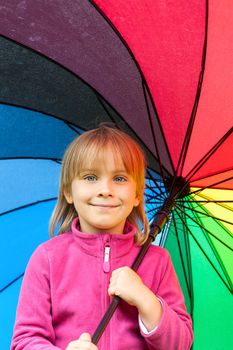 Portrain of little girl wearing pink fleece jacket holding colorful umbrella