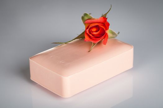 Pink soap with rose flower on gray background