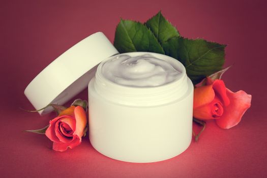 Face cream with roses on pink background. Beauty treatment 