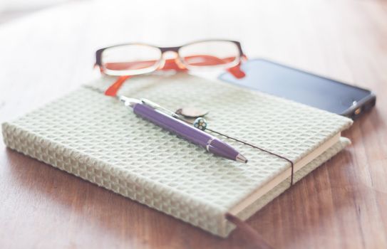 Notebook and pen with eyeglasses on wooden table, stock photo