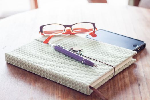Notebook and pen with smartphone on wooden table, stock photo