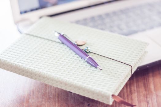 Notebook and pen with computer on wooden table, stock photo