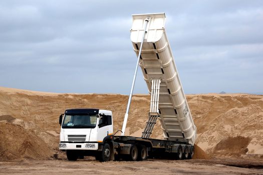 Huge tipper truck with hydraulic lifter in a sand quarry