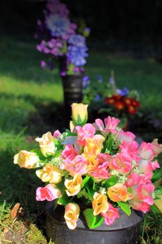 An arrangement of artificial silk roses found in a graveyard setting. Set on a portrait format.