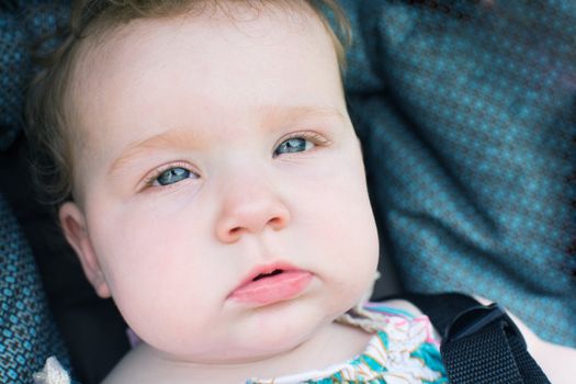 Close up of blue eyed baby in natural light looking at viewer