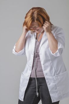 attractive forty year old woman doctor with red hair putting in a stethoscope and laughing