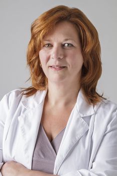 forty year old woman with red hair wearing a doctor lab coat