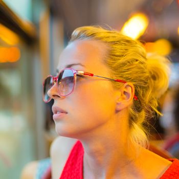 Thoughtful lady riding on a tram and looking out the window. 