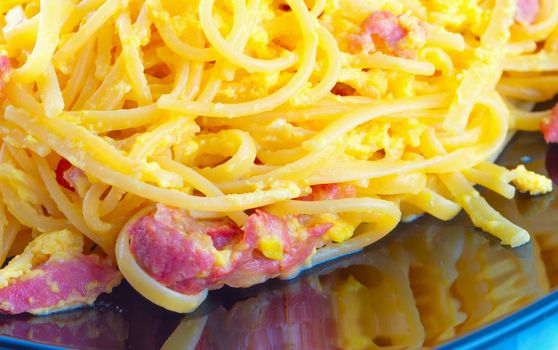 Pasta alla carbonara in close up, over black reflecting plate
