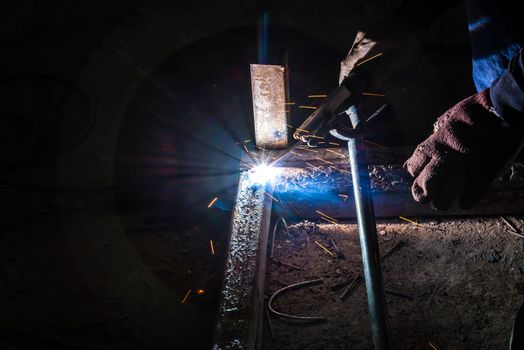 Worker are welding steel on low light.
