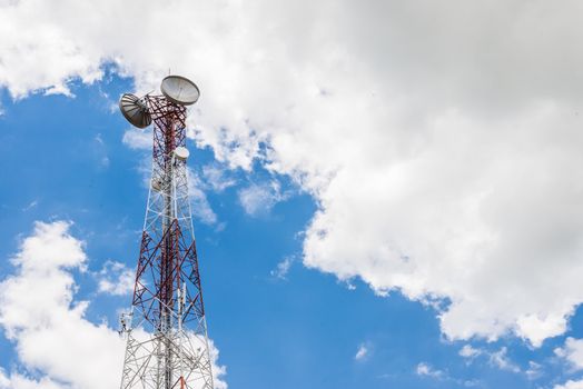 Red and white tower of communications with a lot of different antennas under clear sky.