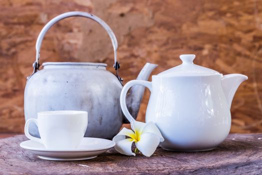 White cup with white tea pot on wood background