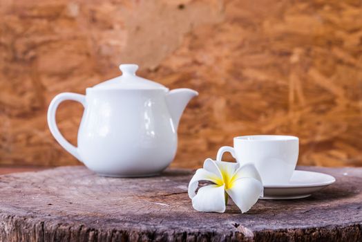 frangipani and White cup with white tea pot on wood background
