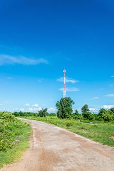 Red and white tower of communications with a lot of different antennas under clear sky.