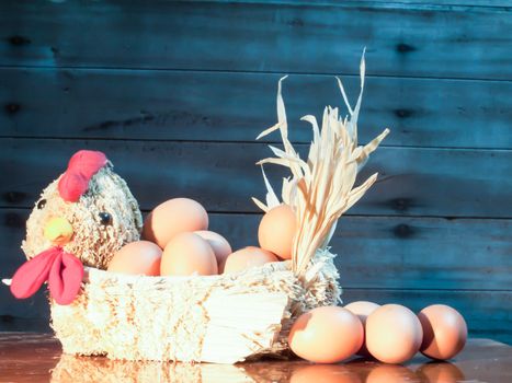 Still light eggs in straw hens on wood and old wood background.