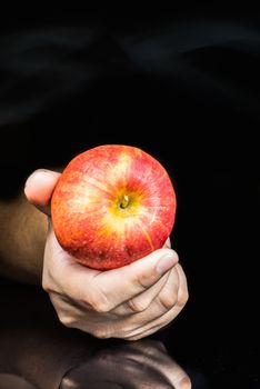 red apple  on hand on black background.