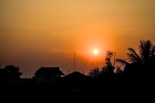 Landscape - sun at sunset with clouds foreground of silhouettes of rooftops