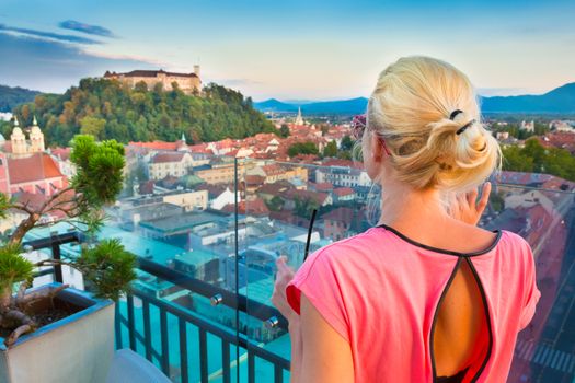 Female tourist enjoying panoramic view of Slovenian capital Ljubljana at sunset.