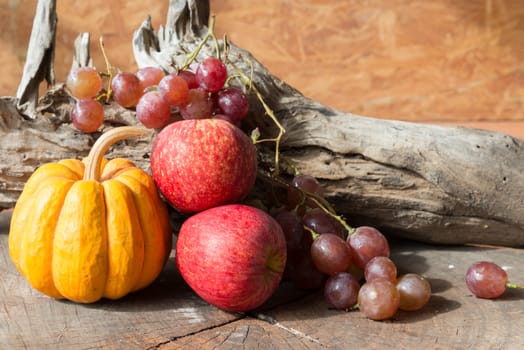 Still life red apples and grapes and pumpkin on old wood.