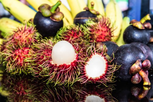 Selection Of Tropical Fruits on black glass background.