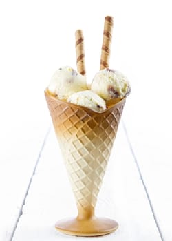 Vanilla ice cream  with wafer in cup on white wooden background