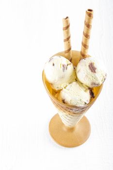 Vanilla ice cream  with wafer in cup on white wooden background