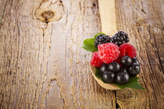 Fresh berries in wooden spoon on wooden table