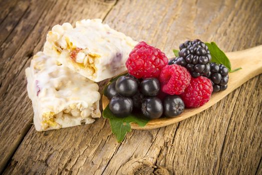 Muesli bars with fresh berries on wooden background