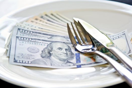 American Dollar note on white plate by cutlery