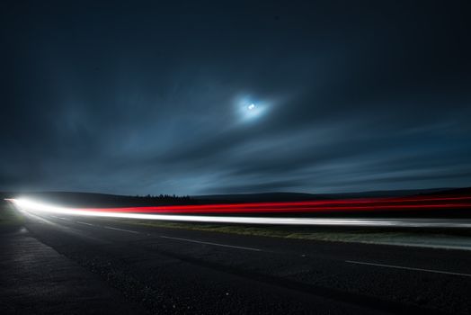 Blur light in night shoot of fast driving car with blurred clouds over full super moon and road