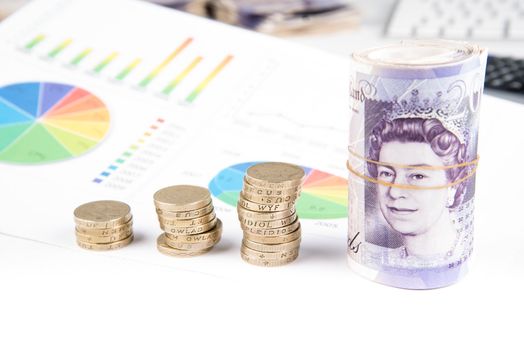 British pound sterling coins and notes with financial chart in background