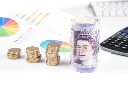 British pound sterling coins and notes with financial chart in background