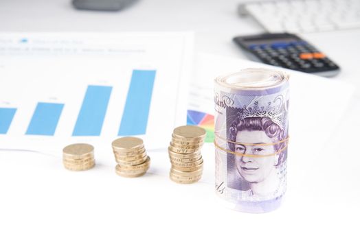 British pound sterling coins and notes with financial chart in background