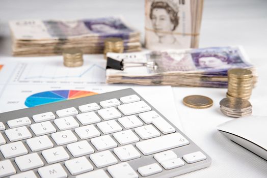 British pound sterling coins and bank notes on desk with keyboard