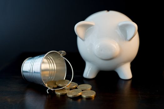 white piggy bank isolated on black background with coins