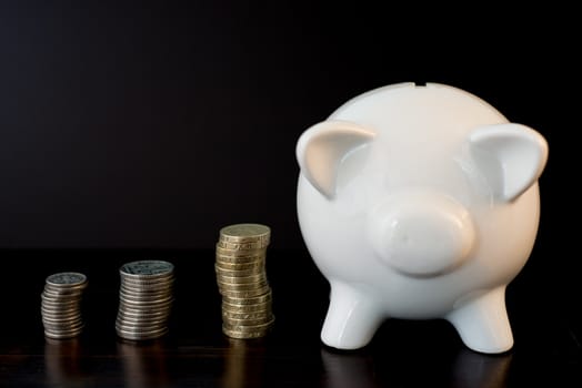 white piggy bank isolated on black background with coins