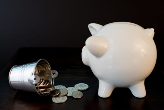 white piggy bank isolated on black background with coins