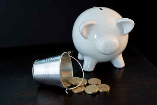 white piggy bank isolated on black background with coins