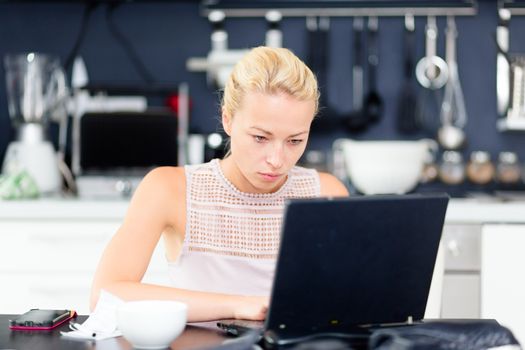 Business woman working remotly from her dining table. Home kitchen in the background.