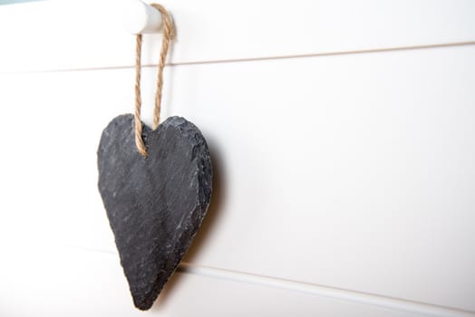 Black stone slate herath shape blank sign hanging on white wooden door