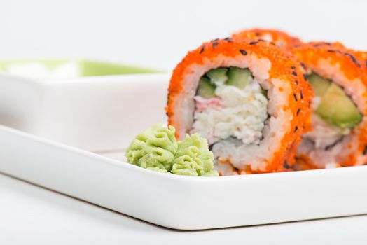 Macro shot of wasabi with sushi rolls on back