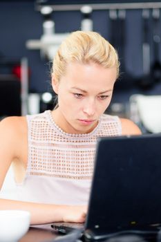 Business woman working remotly from her dining table. Home kitchen in the background.