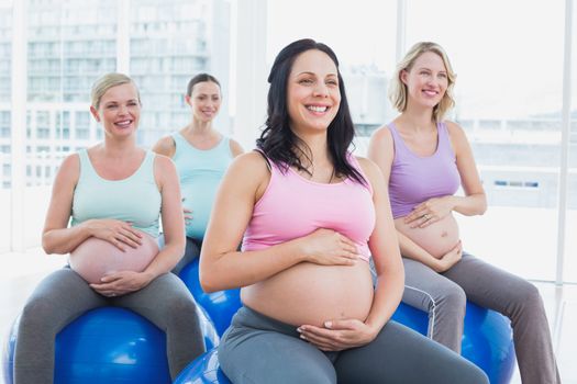 Happy pregnant women sitting on exercise balls in a fitness studio