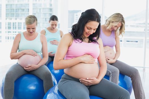 Cheerful pregnant women sitting on exercise balls in a fitness studio