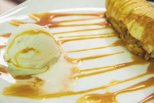strudel on a white plate with ice cream and caramel