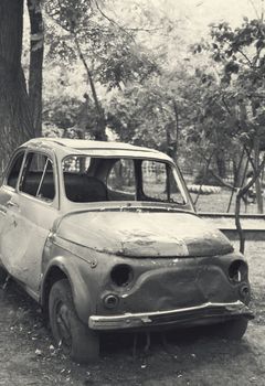stationary old  wrecked car in garden. Vertical monochrome photo