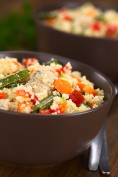 Two bowls of couscous dish with chicken, green bean, carrot and red bell pepper (Selective Focus, Focus in the middle of the dish) 