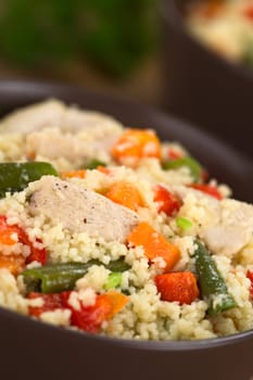 Couscous dish with chicken, green bean, carrot and red bell pepper served in a bowl (Selective Focus, Focus one third into the dish) 